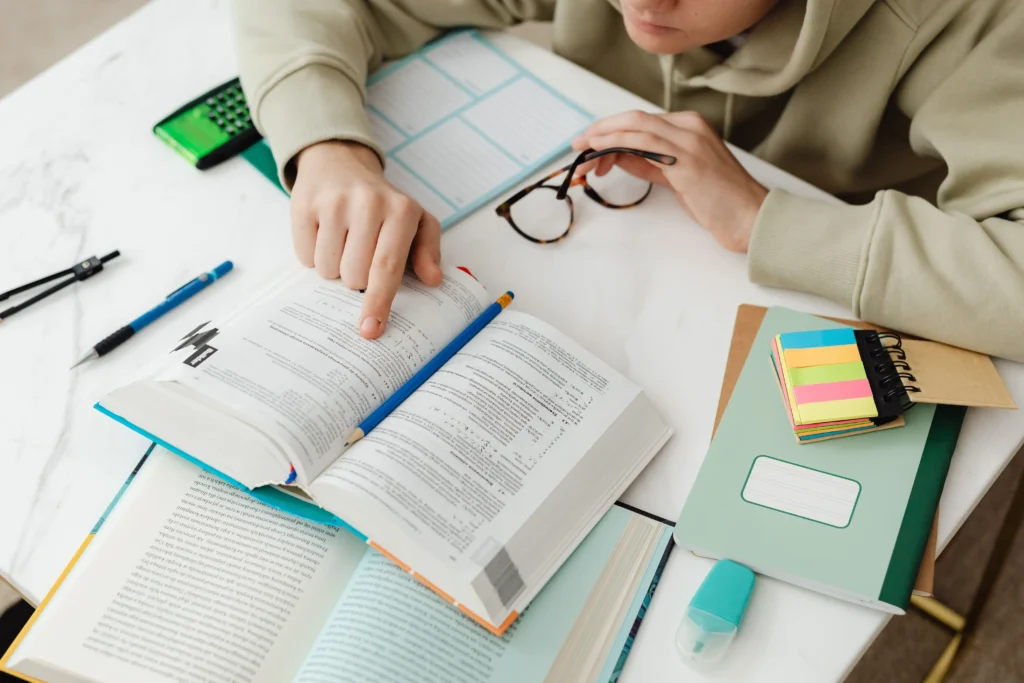 A learner’s desk with opened PMP textbooks, sticky notes, and planner showcasing a structured study routine for certification prep