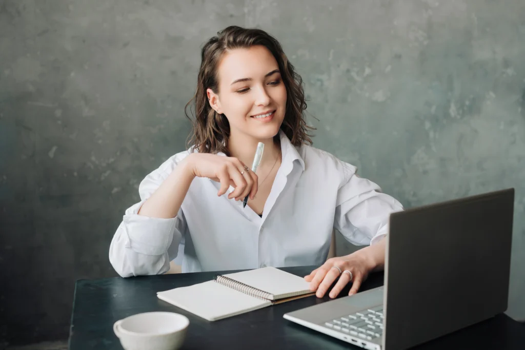  A woman studying online with a notebook and laptop, showing the flexibility and isolation of self-paced PMP training for professionals.